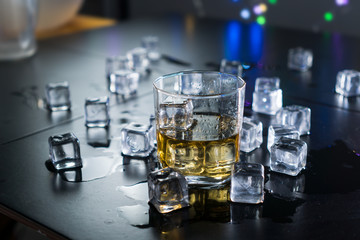 Close up whiskey in glass with ice cubes.dark black background.