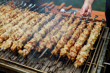 Grilled shish kebab on metal skewer. Chef hands cooking roasted meat barbecue with lots of smoke.
