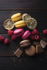 Group of colorful macarons with their ingredients over a wooden table