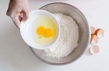 Hand pouring egg yolk mixing with flour to making bread or cake,bakery cooking