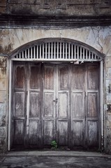 Fototapeta na wymiar Old ancient wooden swing door background. Vintage of old wooden folding doors texture. Antique swing doors or folding doors at old wooden commercial building.