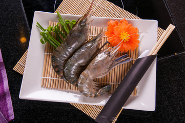 fresh shrimp ready for cooking on white dish and black table background