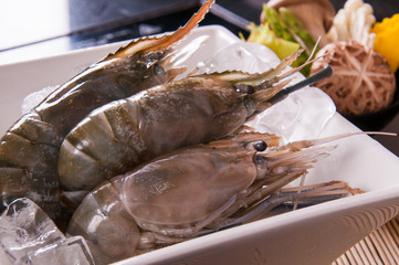 fresh shrimp ready for cooking on white dish and black table background