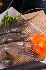 fresh shrimp ready for cooking on white dish and black table background
