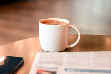 Coffee cup with newspaper and mobile phone on wooden table