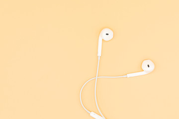 Top view of White Earphones on Orange background. Copy space