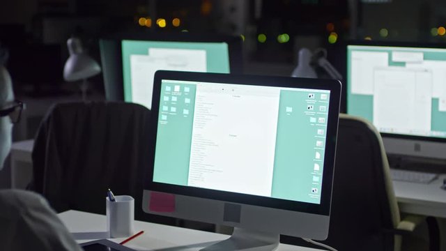 Panning Shot Of African Businessman Sitting In The Office At Night And Writing Report On Computer