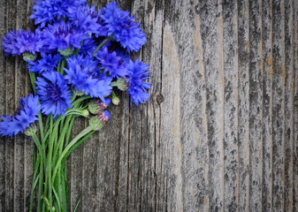 Cornflower blue flowers (Centaurea cyanus) on an old wooden table. Top view.