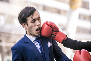 Businessman was knockout by another competition in the boxing glove. Businessman was Punched in the Face at the City Background. Business situation concept. - obrazy, fototapety, plakaty