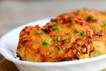 Golden potato burgers with ham on a white plate. Simple roasted potato ham burgers recipe. Closeup
