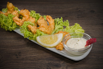 Fried prawns on a plate with sauce and on a wooden background
