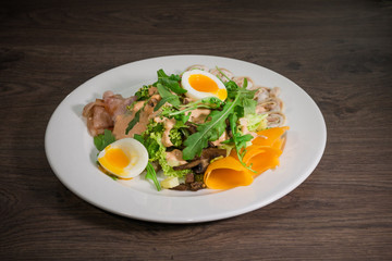 Salad with egg and mushrooms on a white plate and a wooden background
