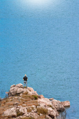 man standing on the rock near the blue sea