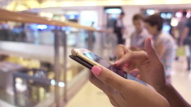 smartphone in woman hands in shopping mall background