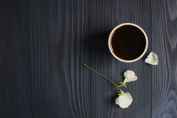 A cup of black coffee and a flower of sweet pea