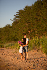 Fototapeta premium A young couple in love, on the shore of the Bay at sunset