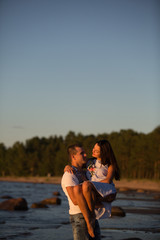 Fototapeta premium A young couple in love, on the shore of the Bay at sunset