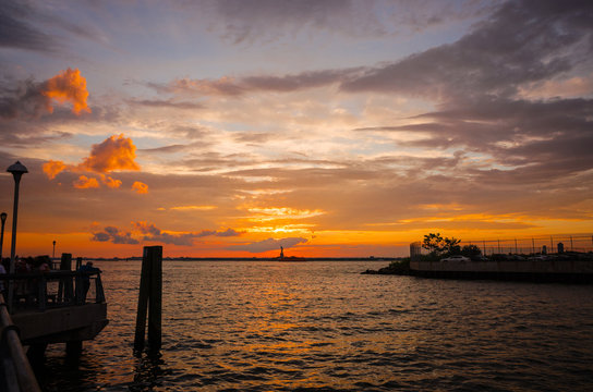 絶景、ハドソンリバーの夕暮れ / New York のシンボル自由の女神の向こうNew Jersey に夕日が沈み、美しい夕焼け雲が広がります。