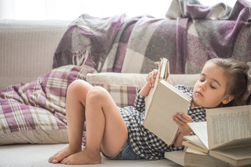little girl reading book on sofa