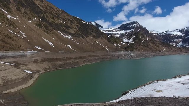 Aerial view on Ritom lake between snow-capped mountains at spring, Switzerland alps, 4k
