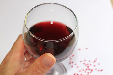 A closeup of a girls hand holding a glass of red vine