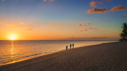 Fototapeta na wymiar Thtree silhouette running on the beach at sunset in Mauritius.