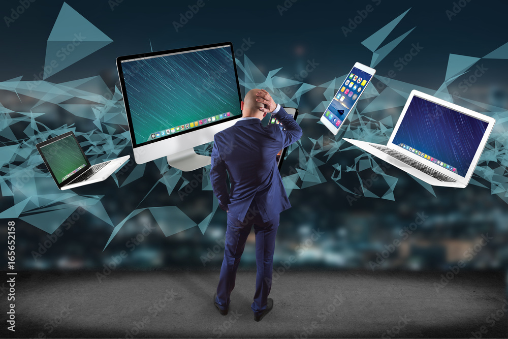 Poster businessman in front of a wall with computer and devices displayed on a futuristic interface with in