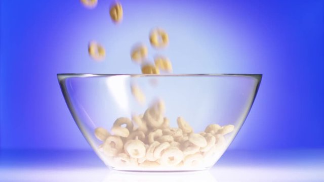 Pour cereal rings and milk in glass bowl on purple