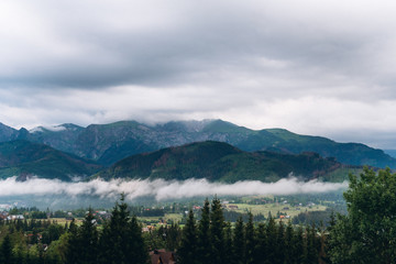Obraz premium Beautiful landscape of cloudy mountains near the village