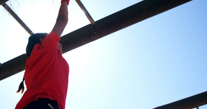 Girl climbing on monkey bar in the boot camp