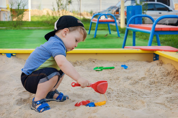 Fototapeta na wymiar Charming cute boy playing in the sandbox on the playground