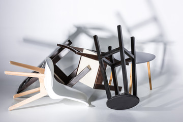 Pile of different modern stylish chairs lying on white in studio