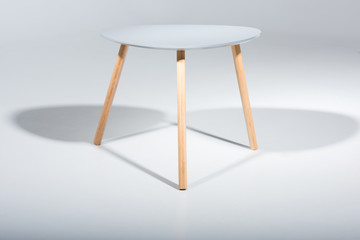 Studio shot of stylish stool with white top and light wooden legs standing on white