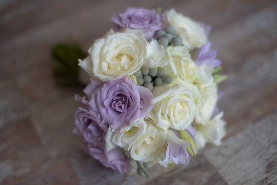 Pastel bridal round bouquet with purple and white roses. Floral arrangement ideas for the bride and bridesmaids
