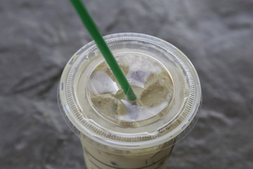 ice coffee in plastic glass with green straw on granite background  .