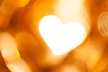 Glowing golden blurred background with heart. Concept of love
