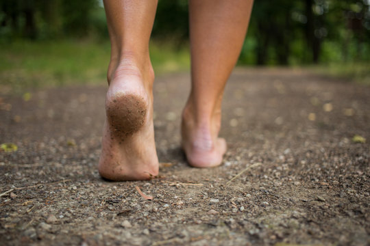 Young woman walking barefoot through the forest