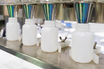 white plastic bottle on the production line of the conveyor at filling machine in the factory. selective focus.