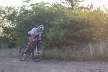 Naklejka premium Male in helmet and sportswear on his cyclocross bike, riding on the country roads 