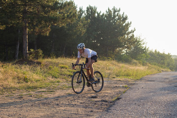 Male in helmet and sportswear on his cyclocross bike, riding on the country roads 