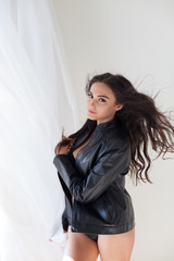 beautiful girl in black lingerie standing by the window in a white room