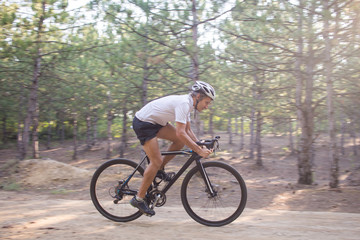 Fototapeta na wymiar Young athlete riding on his professional mountain or cyclocross bike in the forest 