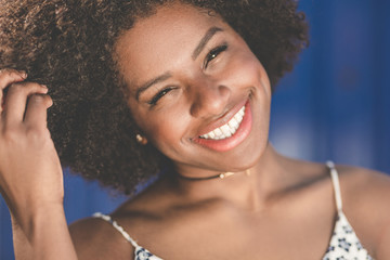 Happy afro american woman tilting head holding hair