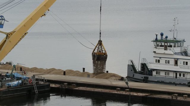 River cargo crane - process of loading sand from the barge to the ship