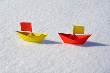 two spanish color paper boats with flags meeting in white background