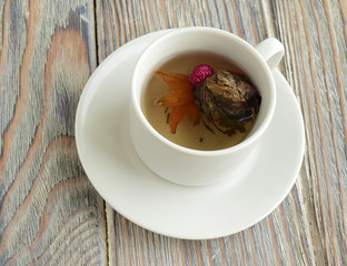 Tea is in a cup. It is white tea with a lotus flower.