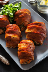 Stuffed chicken rolls in bacon on grey tray