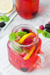 Summer Berry Drink. Lemonade with raspberry and blackberry with lemon, mint in mason jar on gray stone table background