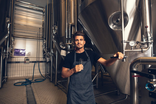 Male brewer standing by tank in brewery