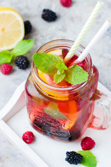 Summer Berry Drink. Lemonade with raspberry and blackberry with lemon, mint in mason jar on gray stone table background. Top view